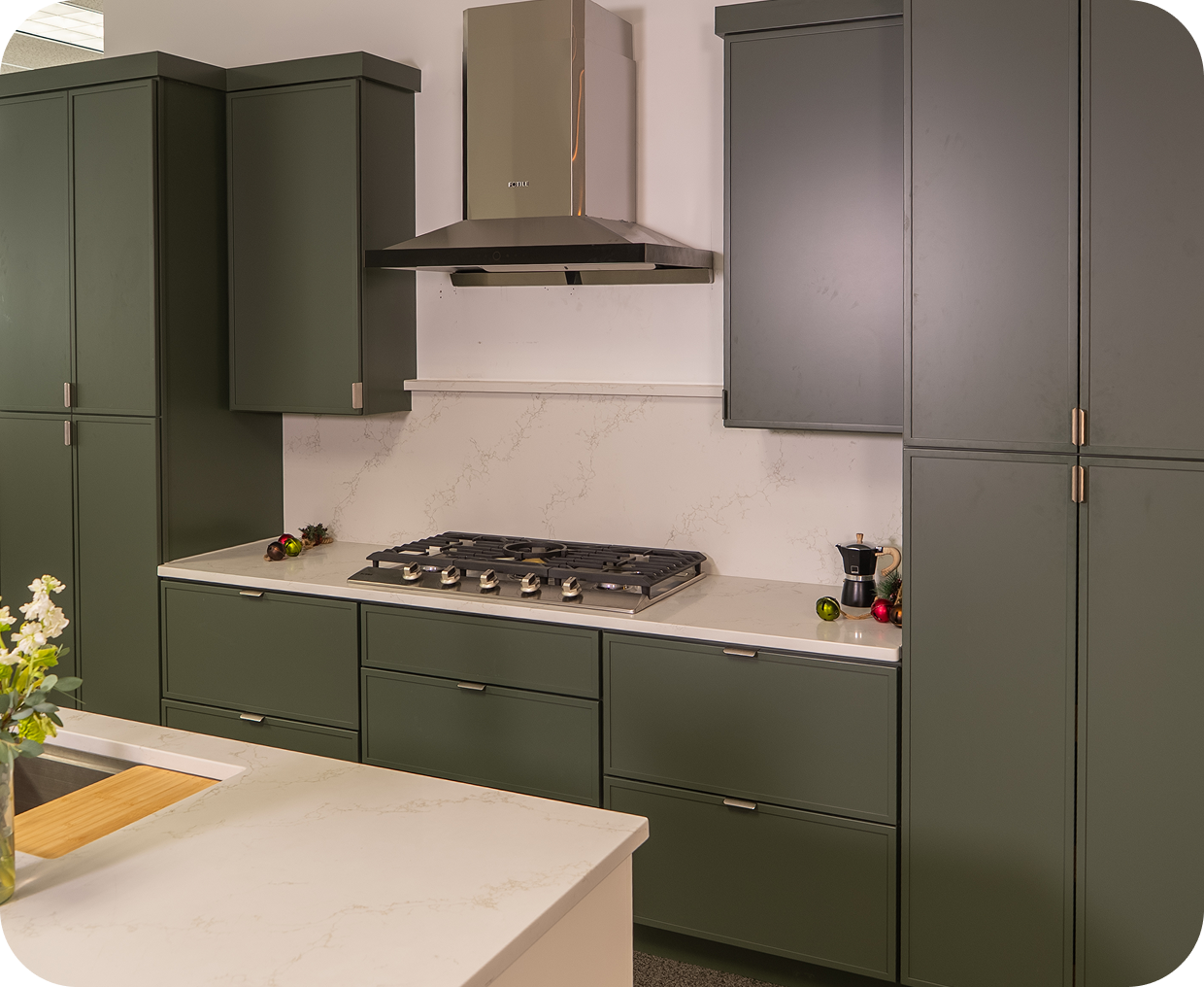 Modern kitchen with olive green cabinets and a gas stove.