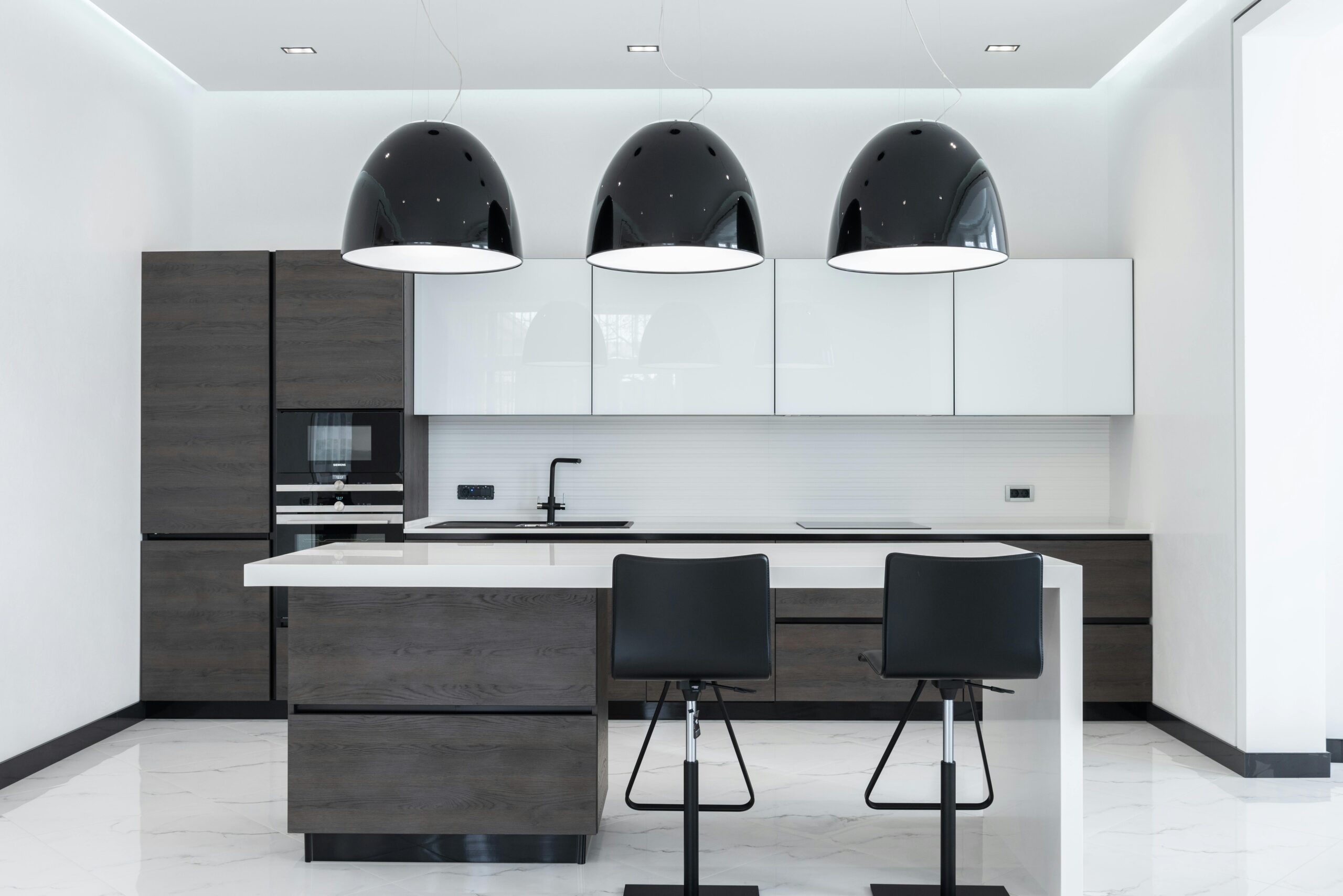 Modern kitchen with dark pendant lights and sleek island seating.