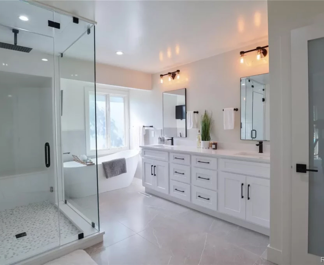 Bright modern bathroom with glass shower and white cabinetry.