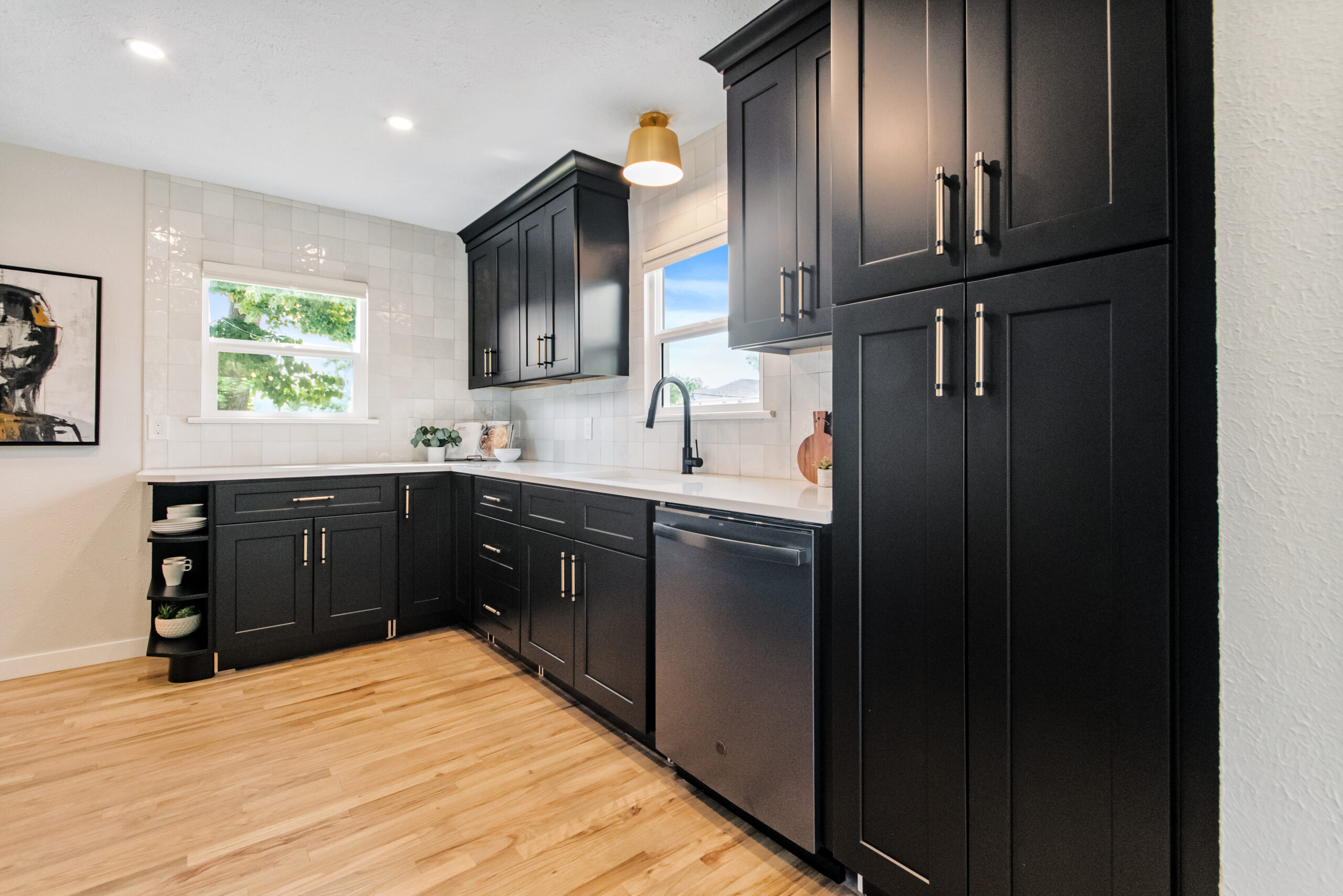 Modern kitchen with black cabinets and wooden floor.