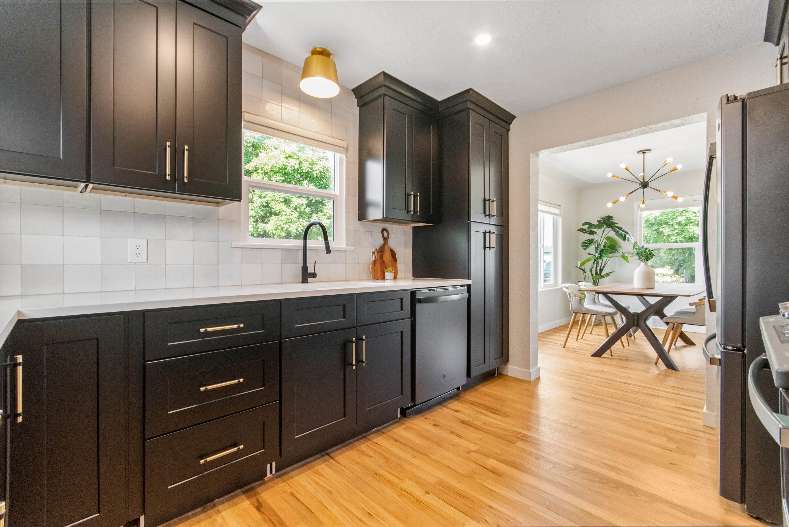 Modern kitchen with black cabinets and wooden floor.