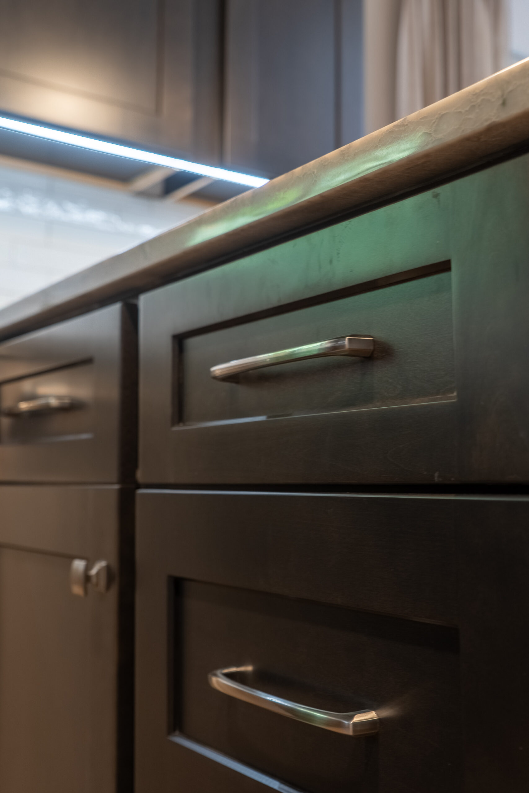Close-up of dark wooden kitchen cabinets with metal handles under a countertop.