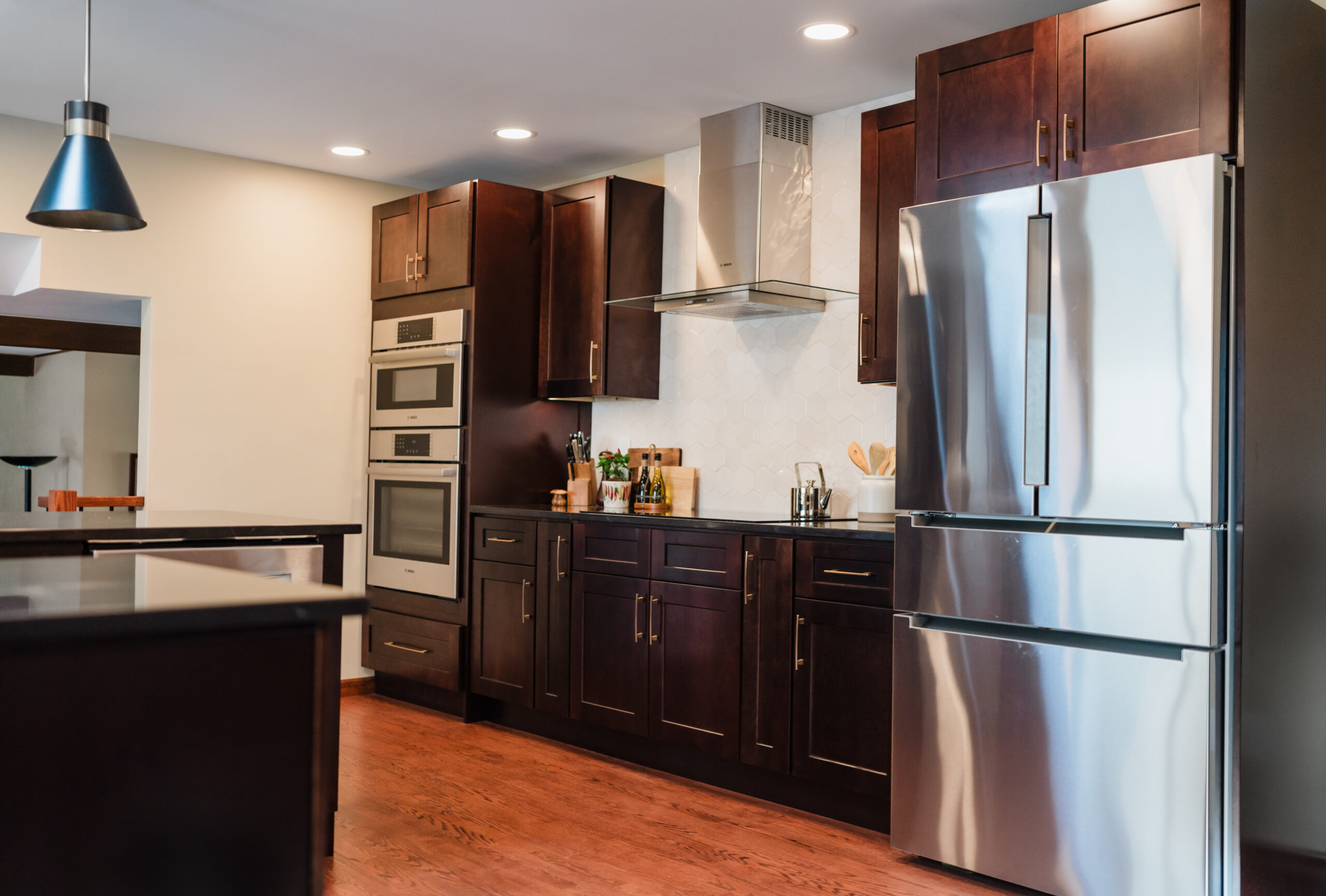 Modern kitchen with stainless steel appliances and dark wood cabinets.