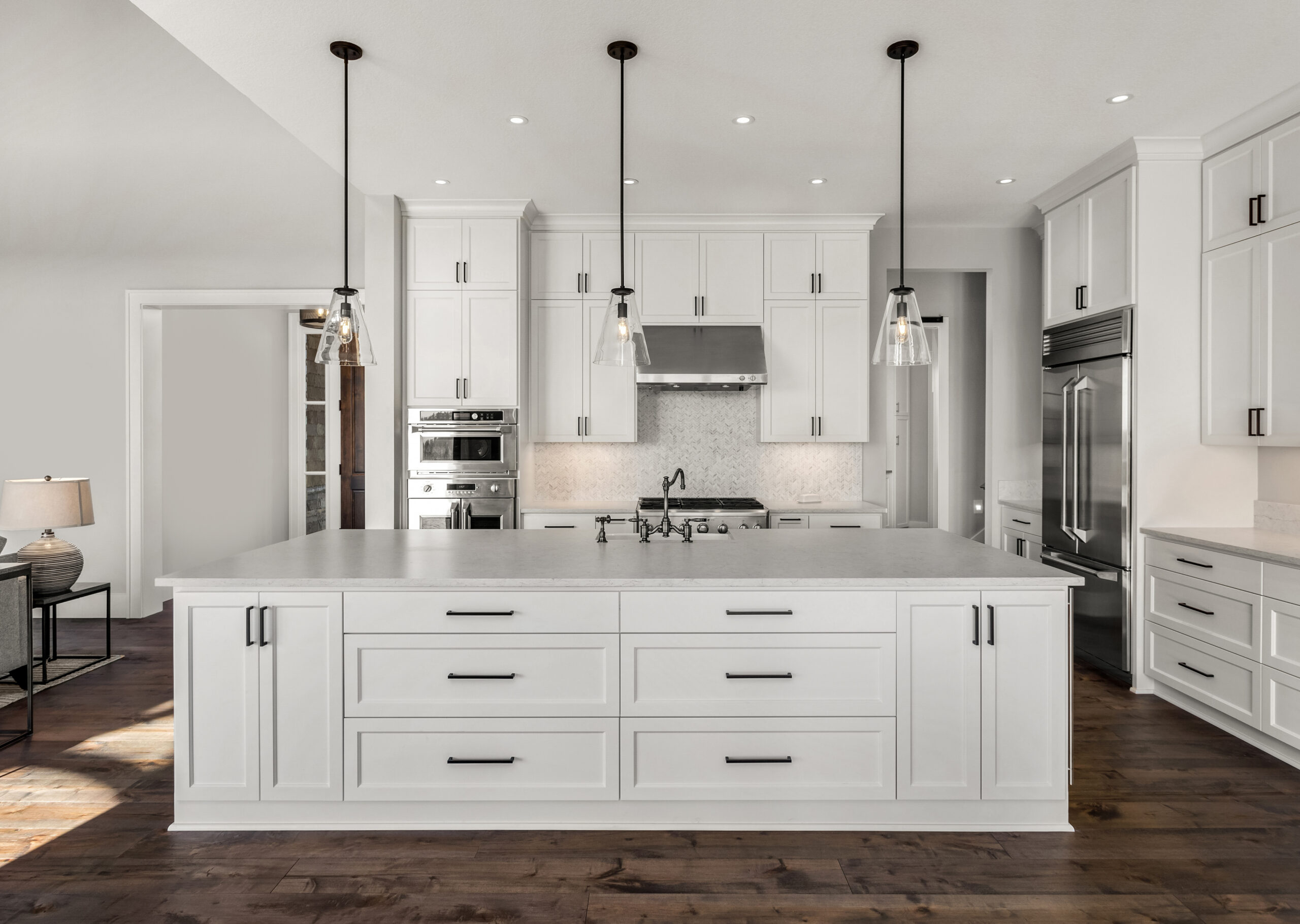 Modern white kitchen with a large island and stainless steel appliances.