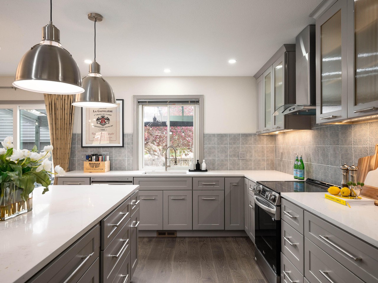 Modern kitchen with gray cabinets and stainless steel appliances.